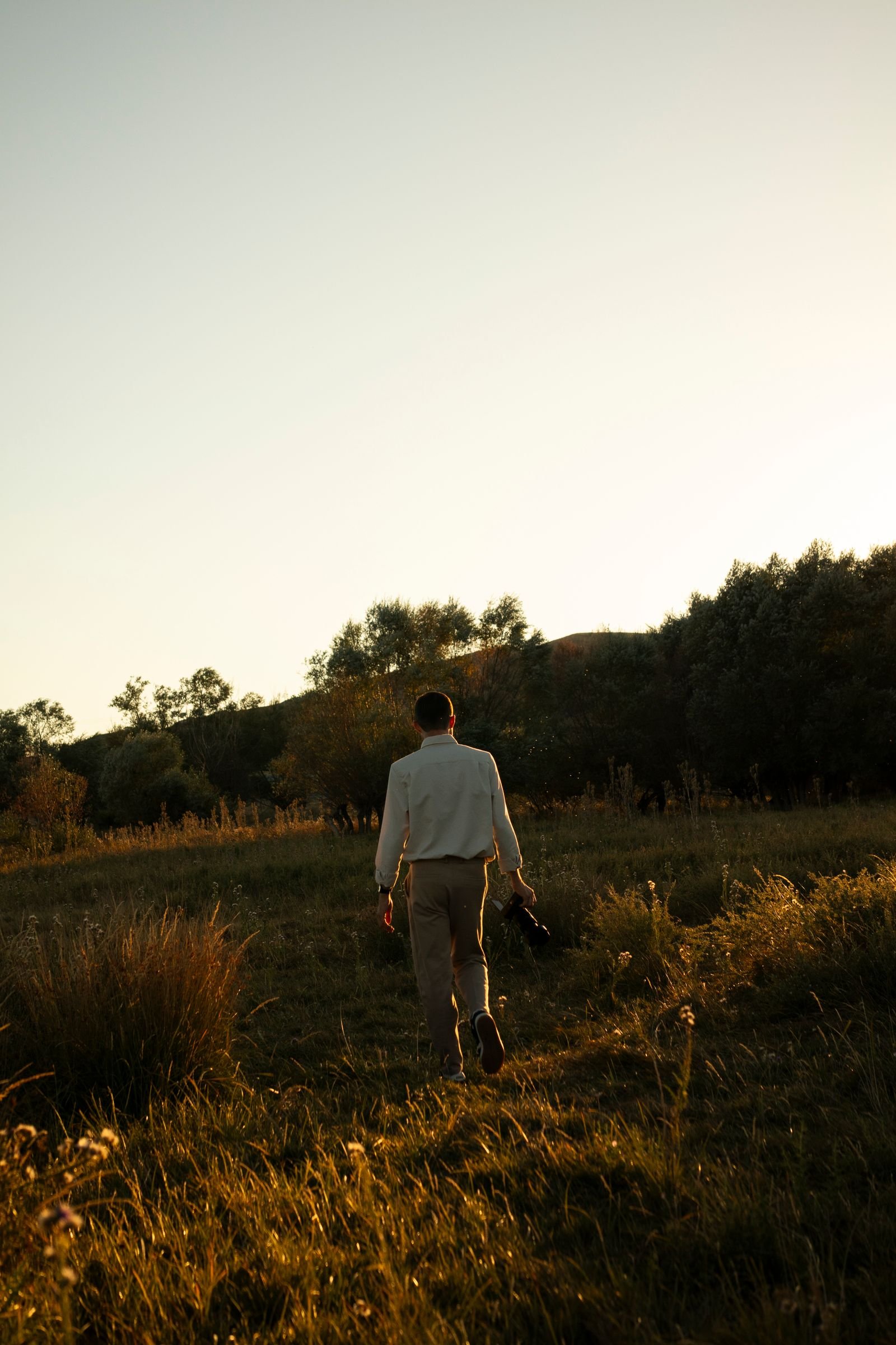 Person walking through a sunlit meadow at golden hour — a picture of resilience