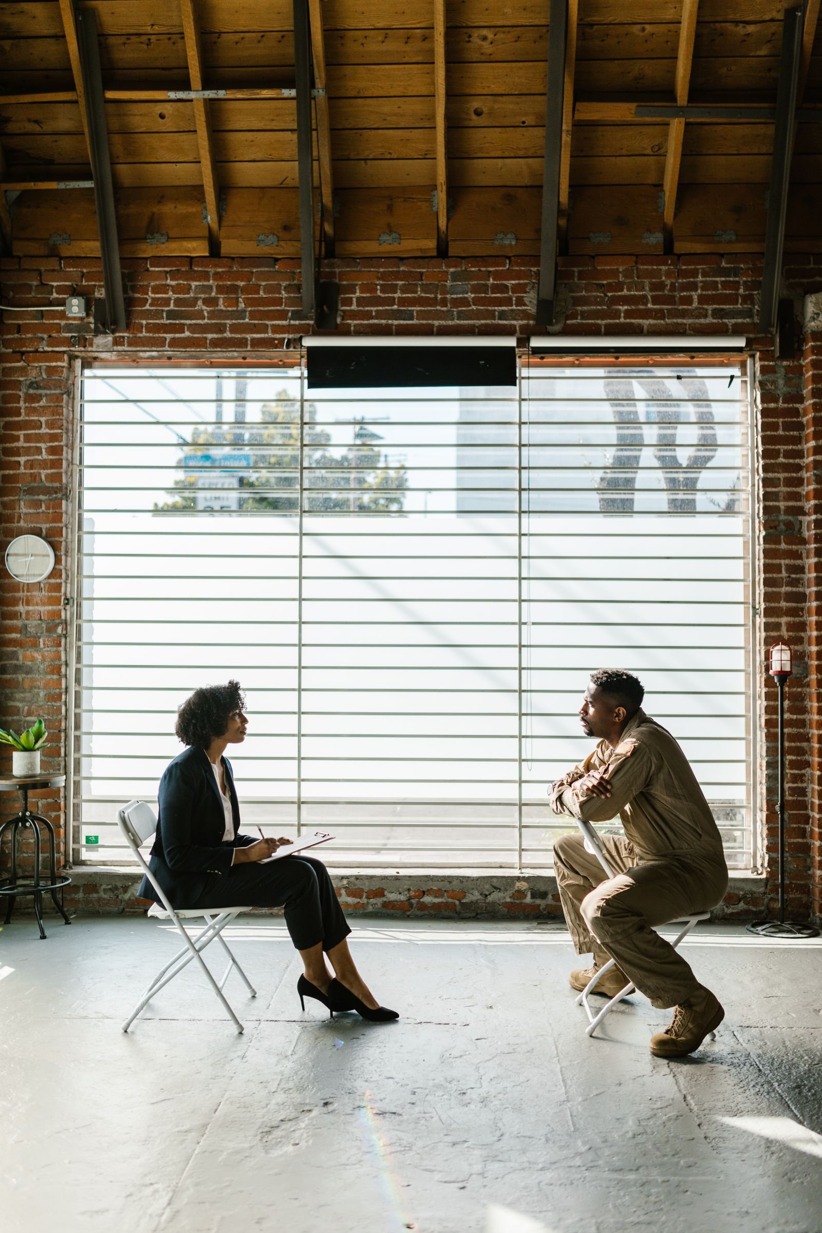 Focused therapy conversation between counselor and patient in a bright studio space