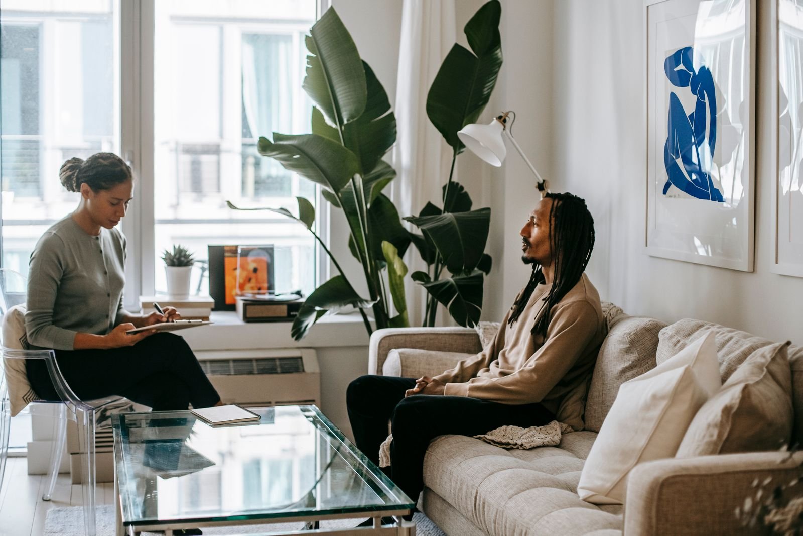 Counselor taking notes while listening to a patient in a relaxed consultation room